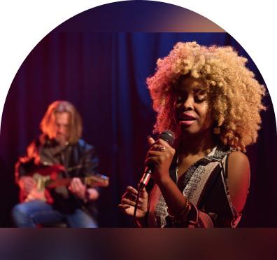 sample-img (4) A woman with curly hair holding a microphone.