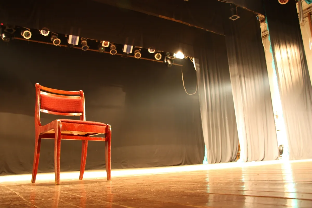 rs=w_1200,cg_true (1) A chair in front of a stage with lights.